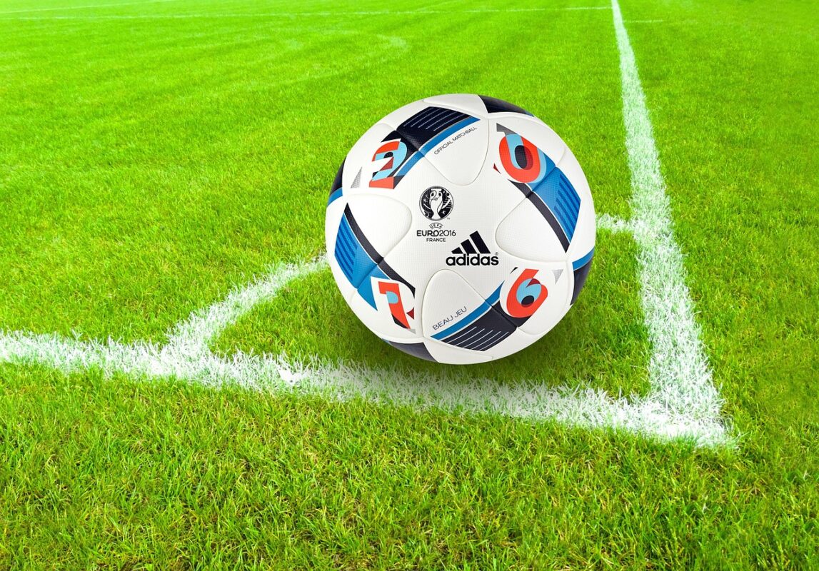 A ball pump with needle beside a soccer ball