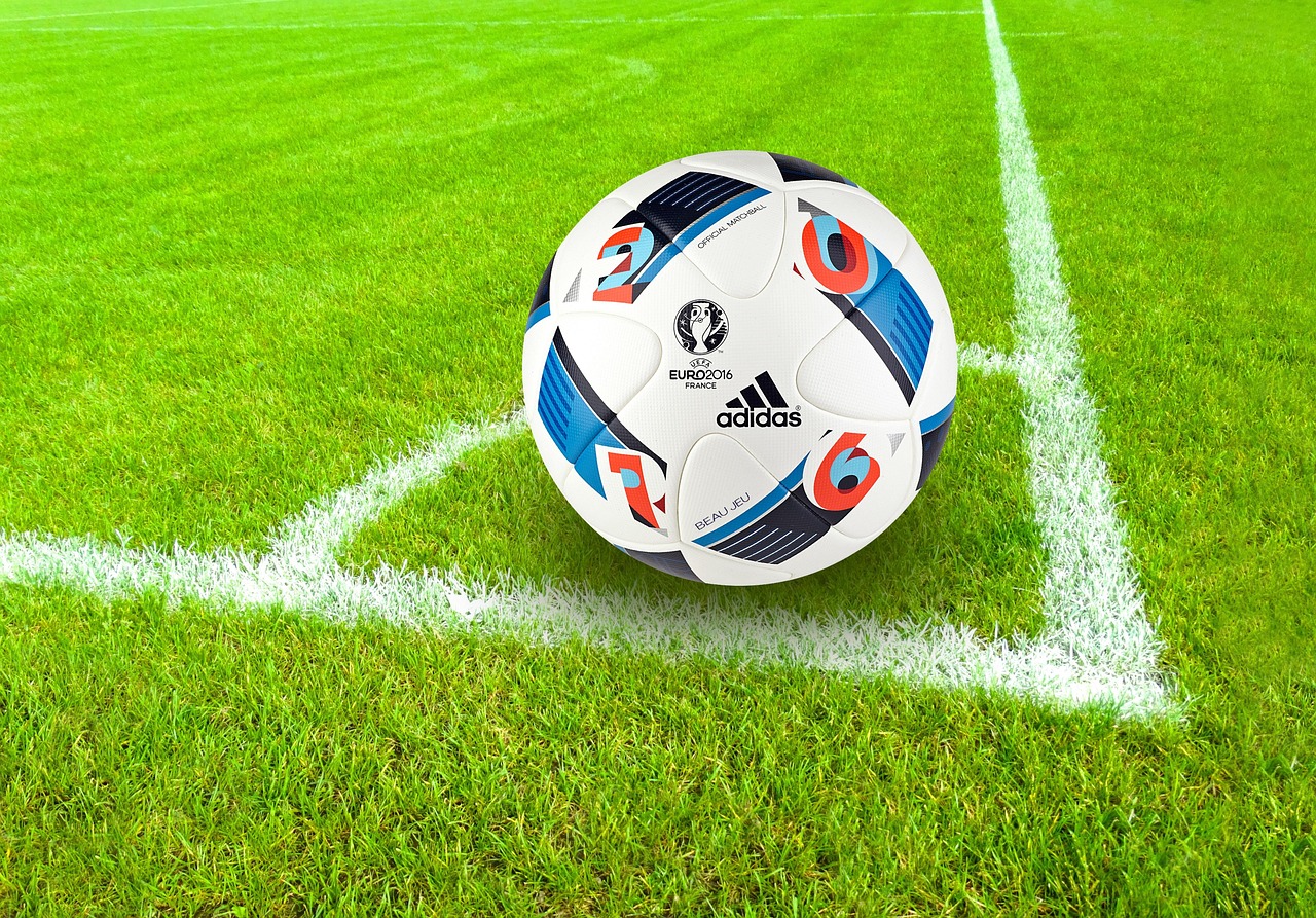 A ball pump with needle beside a soccer ball